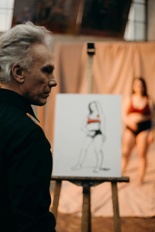 a man standing in front of a painting of a woman, a charcoal drawing, by Gavin Hamilton, pexels contest winner, jean paul gaultier, gary busey, making of, unclad