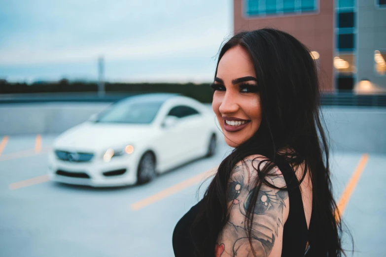 a woman standing in a parking lot next to a car, a tattoo, pexels contest winner, tachisme, smiling seductively, profile image, instagram model, headshot profile picture