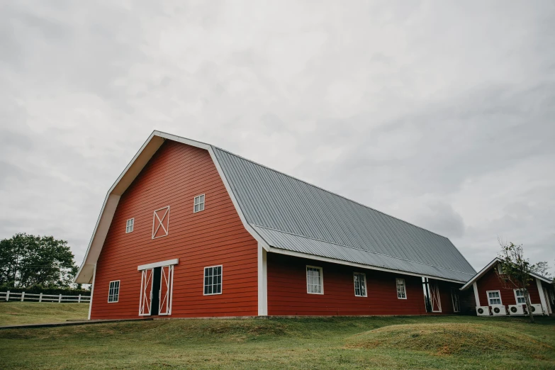 a red barn sitting on top of a lush green field, a portrait, pexels, northwest school, large hall, profile image, overcast, 2 0 2 2 photo