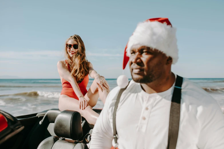 a woman sitting on the back of a boat next to a man in a santa hat, pexels contest winner, shaq, near the beach, blind brown man, camilla luddington