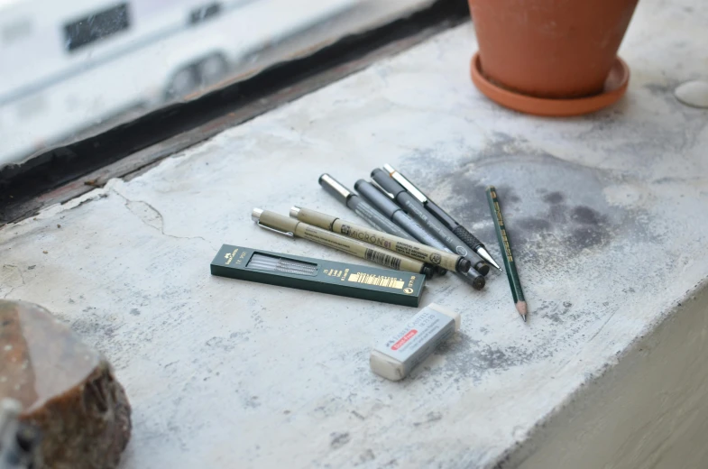 a group of pens sitting on top of a window sill, a still life, architectural scale, murata range, medium: black pencil, full product shot