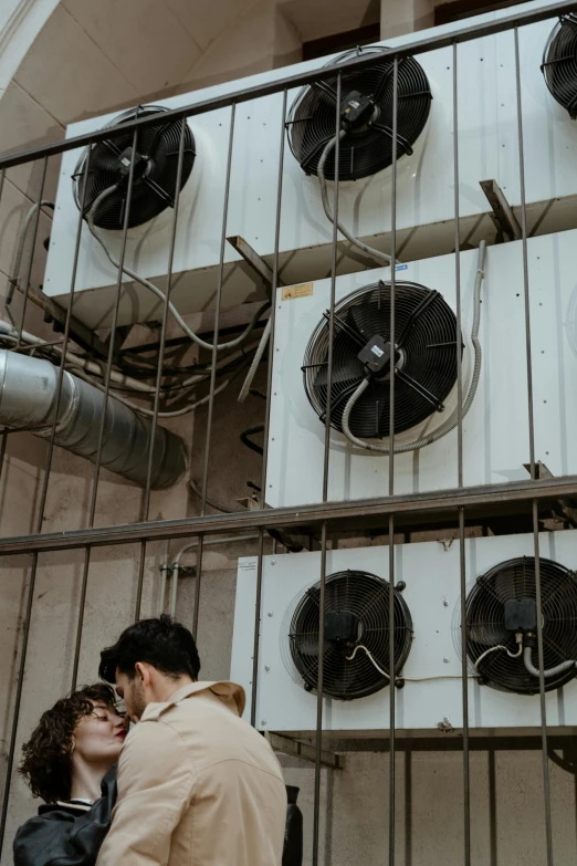 a couple standing next to each other in a building, fans, water-cooled, up there, up close