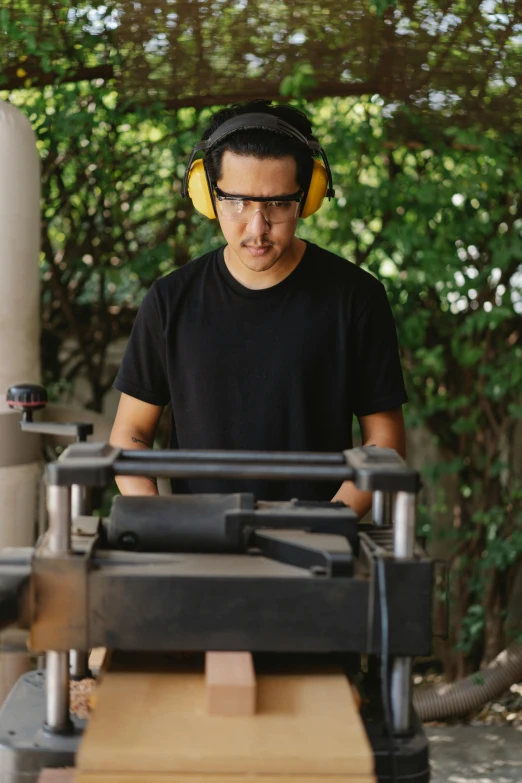 a man using a table saw to cut a piece of wood, inspired by david rubín, wood headphones, looking serious, profile image, hispanic