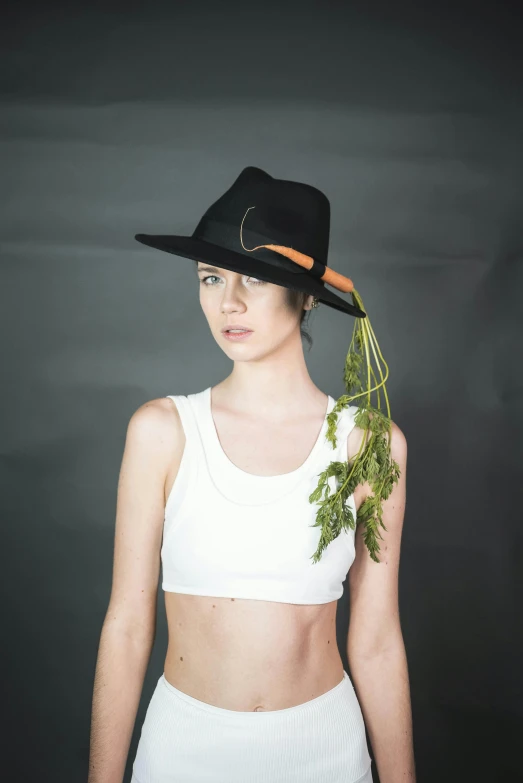 a woman wearing a hat and holding a bunch of carrots, an album cover, inspired by Josefina Tanganelli Plana, unsplash, wearing a cropped black tank top, with green cannabis leaves, at a fashion shoot, profile image