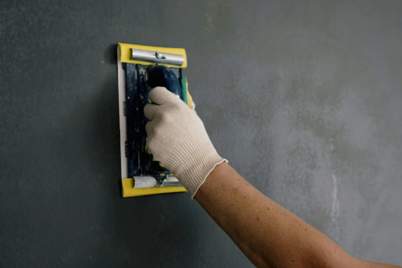 a person using a sponge to paint a wall, a photorealistic painting, arbeitsrat für kunst, holds a smart phone in one hand, chalkboard, yellow latex gloves, scratchy lines