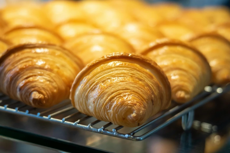 a bunch of croissants that are on a rack, by Tom Bonson, pexels, fan favorite, pastelle, panels, glossy surface