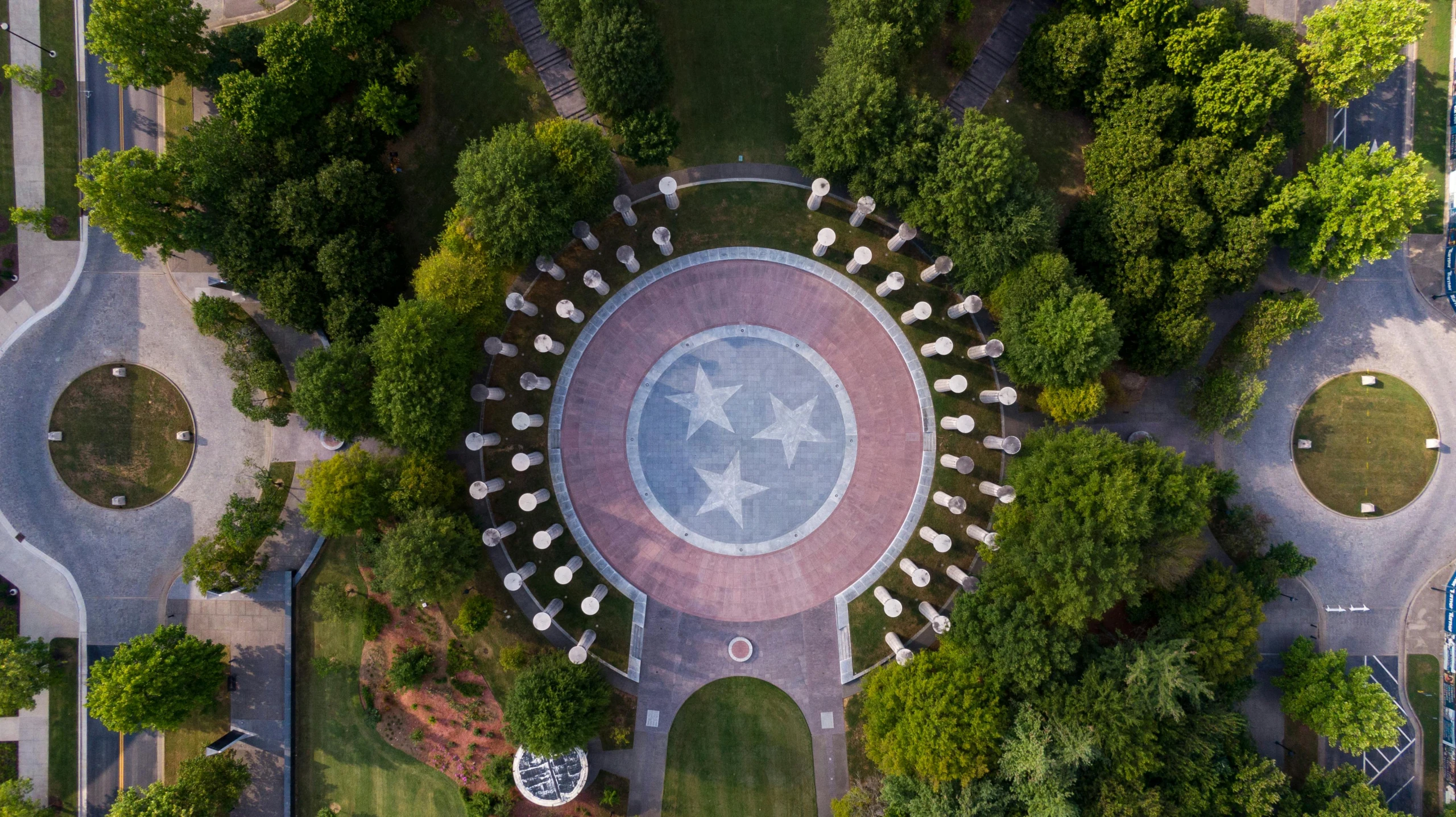 an aerial view of a circular fountain surrounded by trees, a portrait, by Carey Morris, unsplash contest winner, land art, large stone statues of heroes, tn, united states air force, pillars and arches