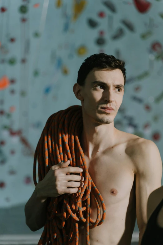 a shirtless man holding a rope in front of a climbing wall, an album cover, reddit, gutai group, portrait mode photo, non binary model, ƒ/5.0, hans bellmer and nadav kander
