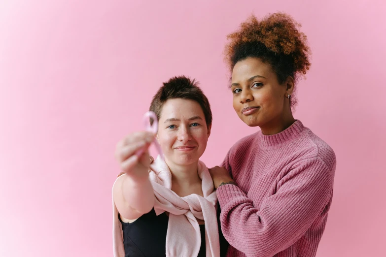 a couple of women standing next to each other, pexels contest winner, ((pink)), holding an epée, mixed race, tumours