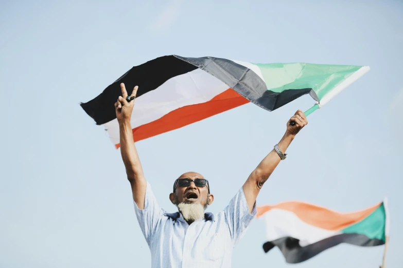 a man holding a flag in the air, pexels contest winner, hurufiyya, civ ghandi, middle eastern skin, with arms up, varying ethnicities