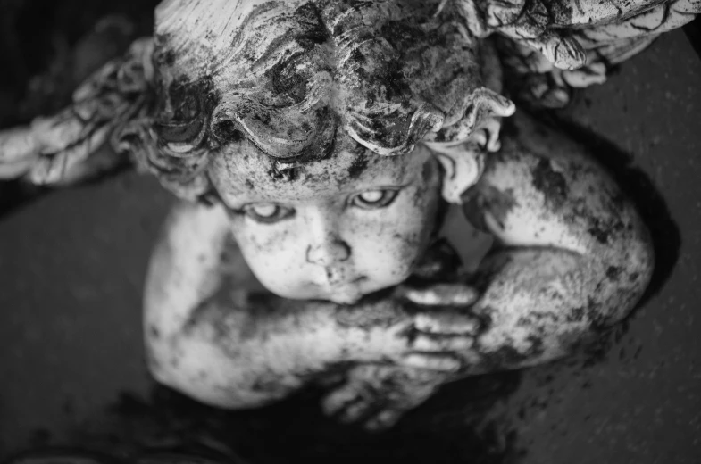 a close up of a statue of a child, by Daniel Lieske, pexels, baroque, high angle close up shot, tattered wings, mono eyed, closeup of an adorable