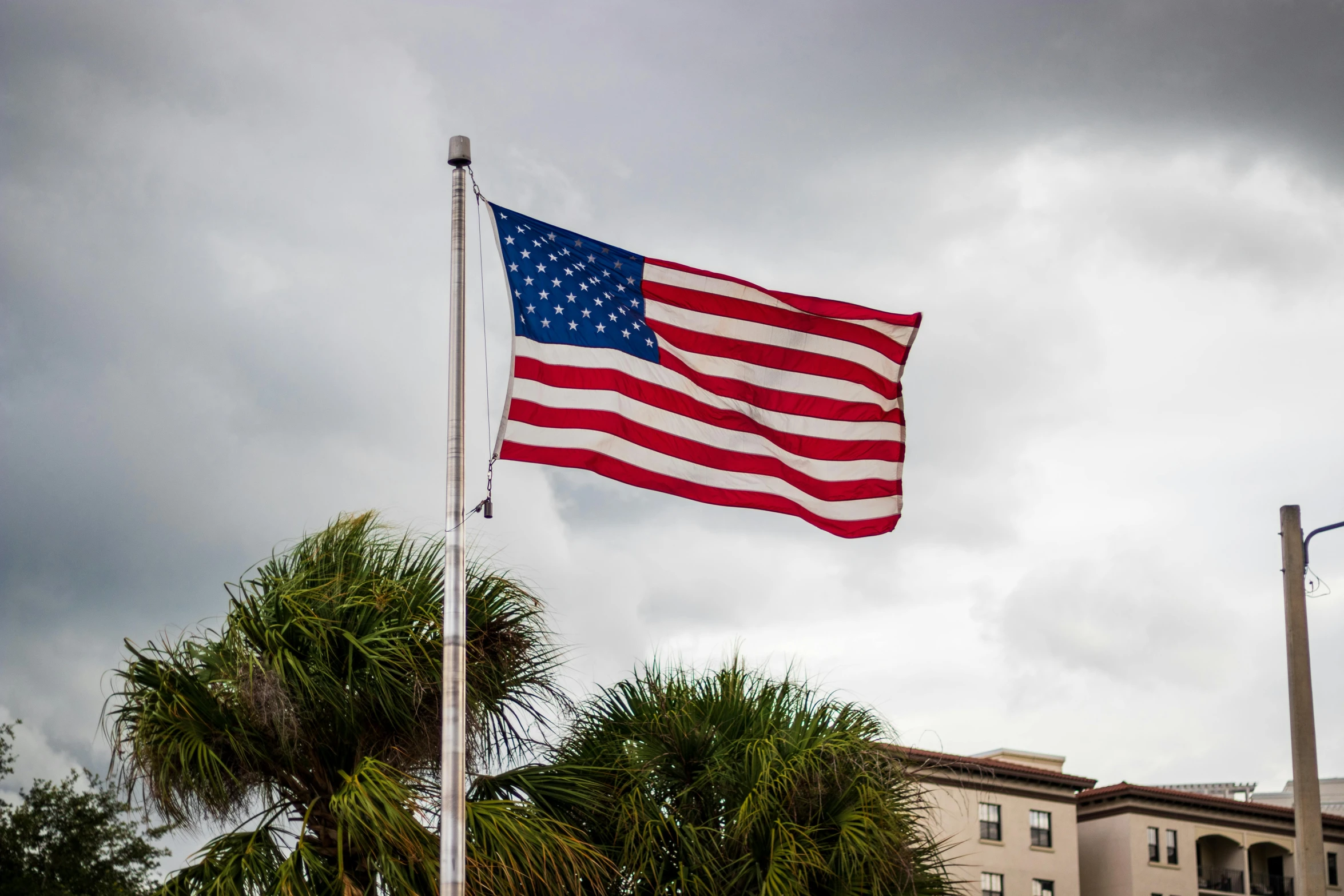 a large american flag flying in front of a building, unsplash, hurufiyya, florida man, nice slight overcast weather, shot on sony a 7 iii, 2000s photo