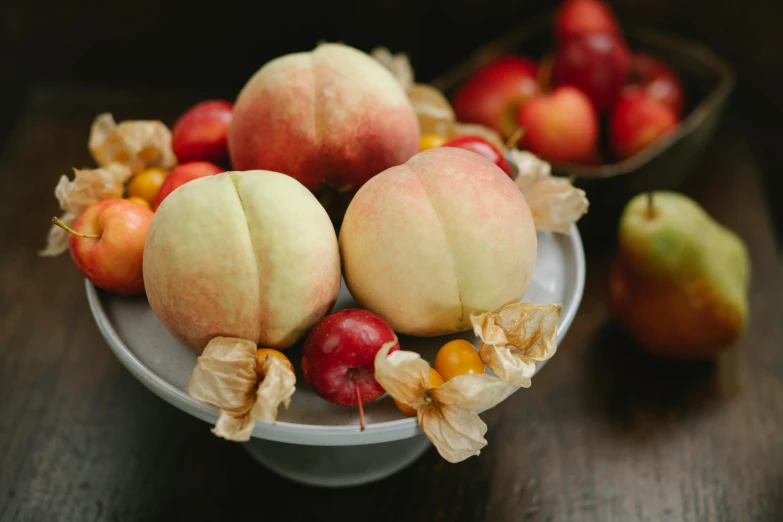 a bowl of fruit sitting on top of a wooden table, on a pedestal, peach, carefully crafted, various sizes