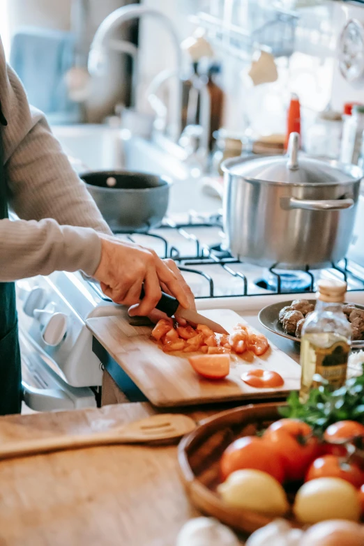 a woman cutting tomatoes on a cutting board in a kitchen, pexels contest winner, steaming food on the stove, upon a peak in darien, center of picture, scene from a dinner party