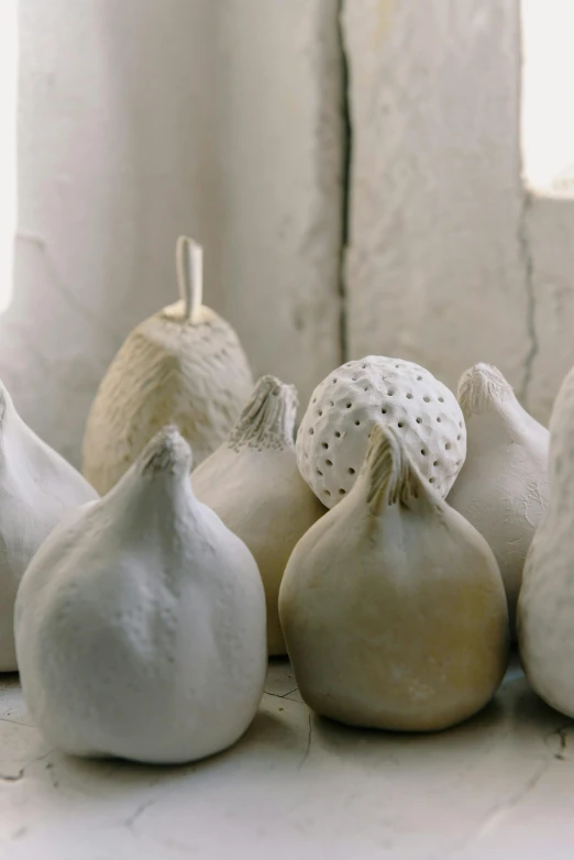 a bunch of garlic sitting on top of a table, inspired by Sarah Lucas, concrete art, white ceramic shapes, domes, pears, handcrafted