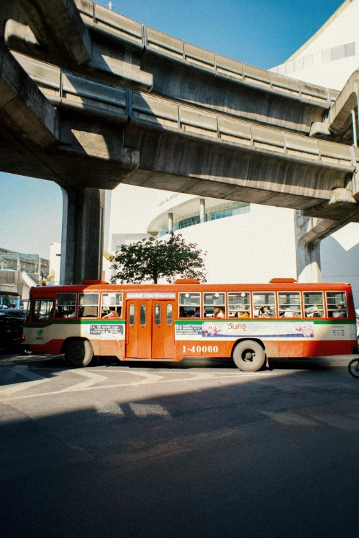 a bus that is sitting in the street, bangkok, under bridge, 1990s photograph, fan favorite