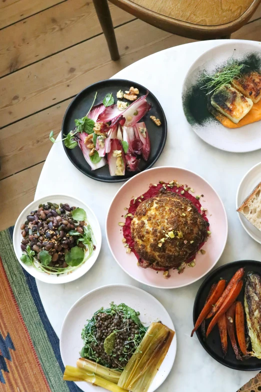 a table topped with plates of food on top of a wooden floor, renaissance, minna sundberg, straya, stuffed, healthy