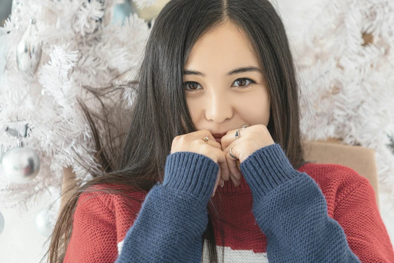 a woman sitting in front of a christmas tree, inspired by Kim Jeong-hui, pexels contest winner, hurufiyya, blue sweater, japanese facial features, teenage girl, avatar image