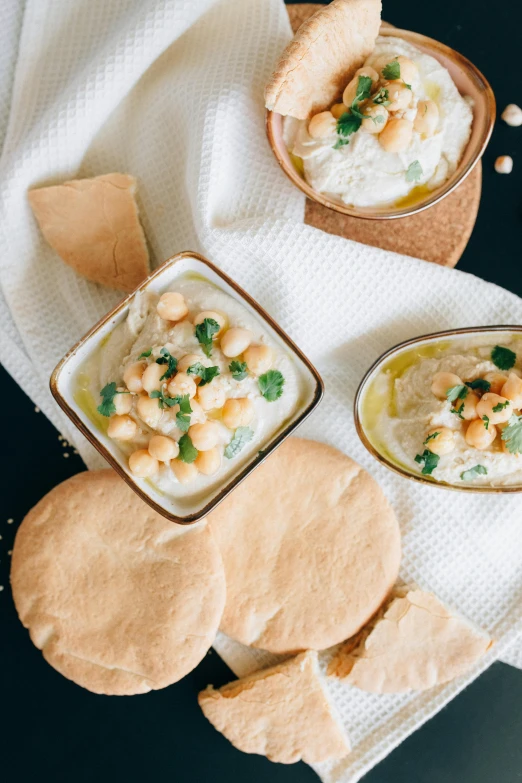 a table topped with bowls of food and pita bread, inspired by Bouchta El Hayani, trending on unsplash, dau-al-set, thumbnail, blonde crea, creamy, therookies