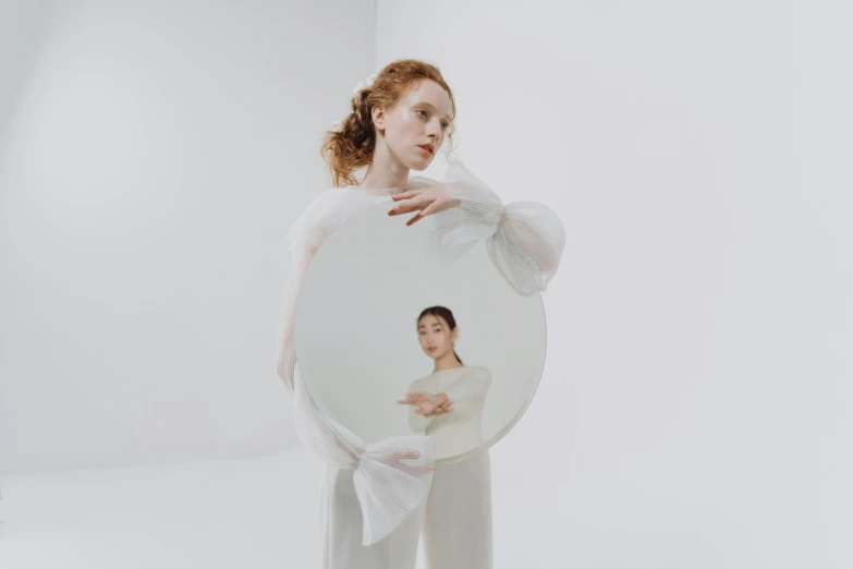 a woman holding a mirror in front of her face, an album cover, inspired by Anna Füssli, eleanor tomlinson, white sleeves, gemma chen, circle