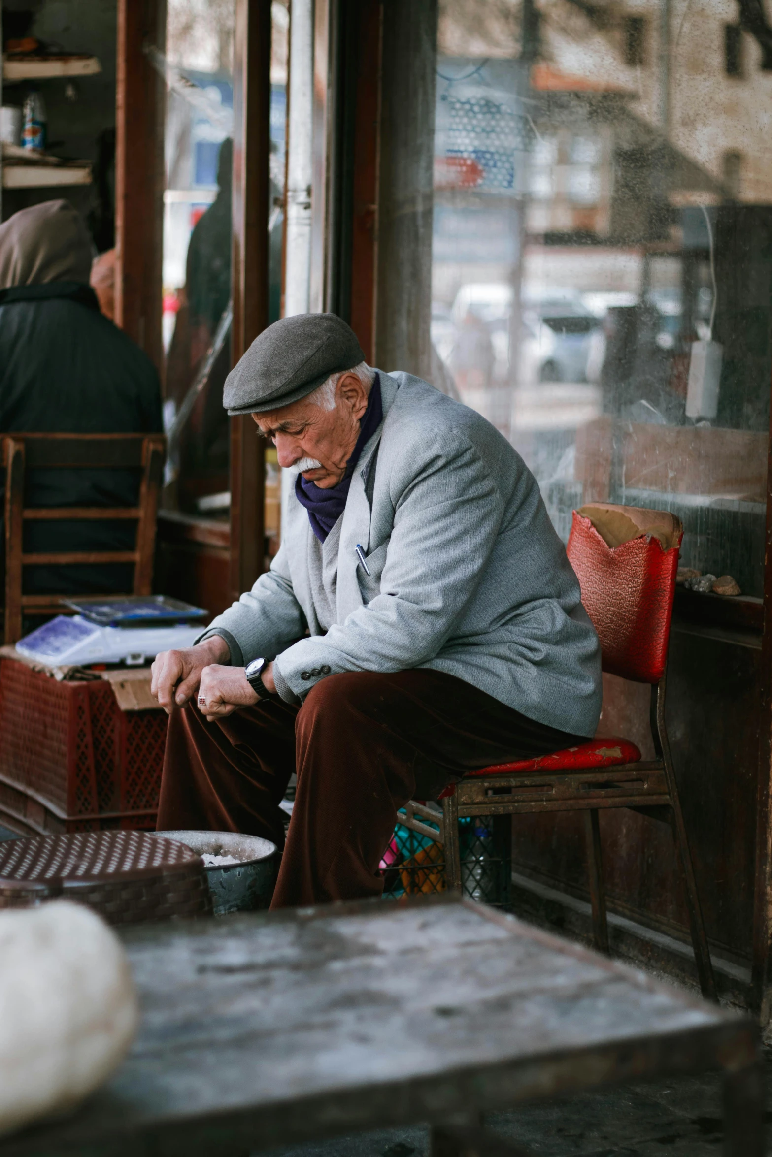 a man sitting on a bench in front of a store, of an old man, top selection on unsplash, iranian, sitting in a cafe