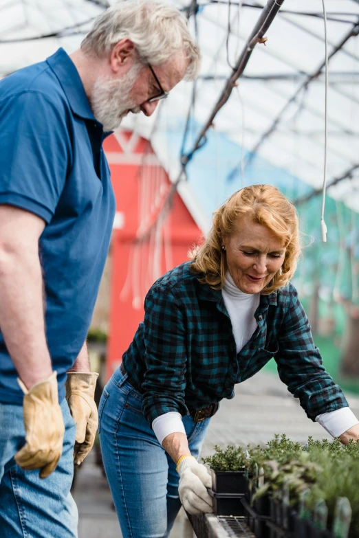 a man and woman looking at plants in a greenhouse, a portrait, pexels contest winner, wearing farm clothes, promotional image, tending on pinterest, looking at the ground