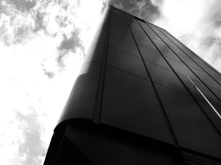 a black and white photo of a tall building, by Dave Allsop, unsplash, metal cladding wall, skies behind, high quality upload, tail fin