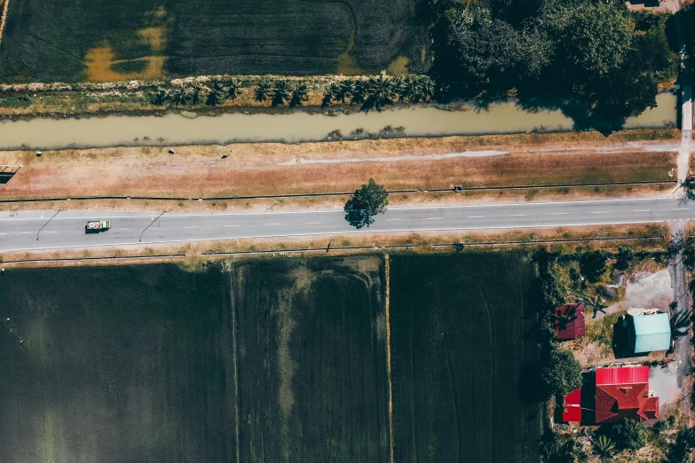 a car driving down a road next to a body of water, by Daniel Lieske, unsplash contest winner, hurufiyya, rice paddies, airplane view, slightly red, flattened