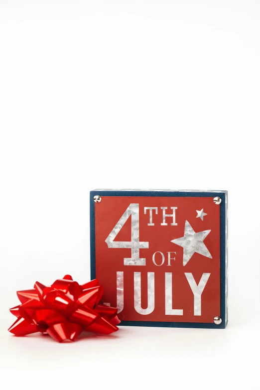 a red, white and blue fourth of july sign next to a red bow, miniature product photo, 1 6 x 1 6, box, - g