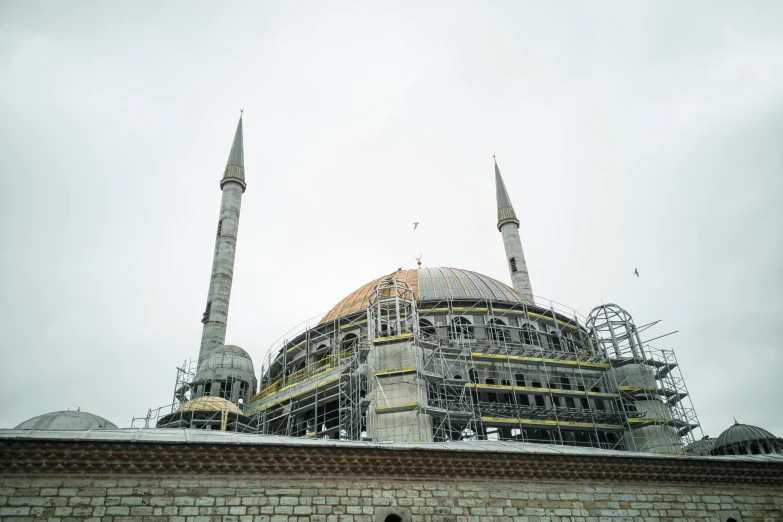 a man standing in front of a building under construction, a colorized photo, pexels contest winner, hurufiyya, dome, back view. nuri iyem, front elevation, slight overcast weather