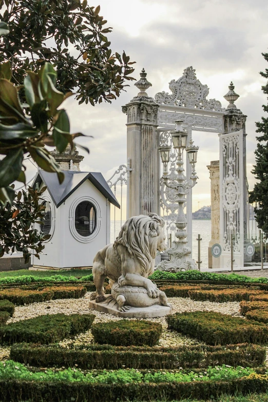 a statue of a lion in the middle of a garden, a marble sculpture, inspired by Serafino De Tivoli, huge gate, on the coast, architectural digest, portugal