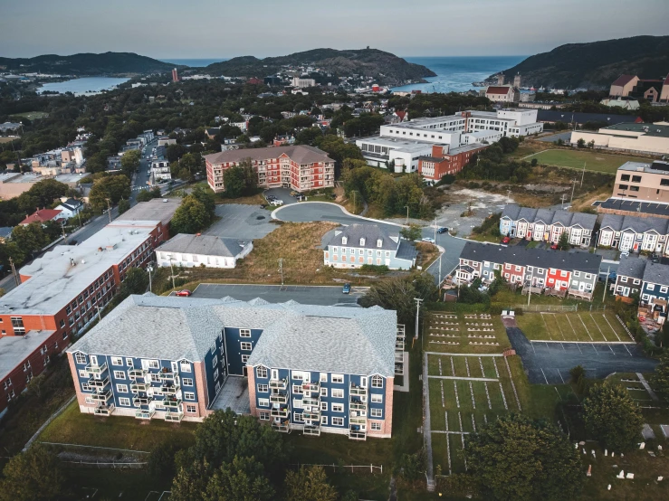 a large building sitting on top of a lush green field, a portrait, unsplash, vancouver school, seaside, realistic photo of a town, stålenhag, wide angle shot from above