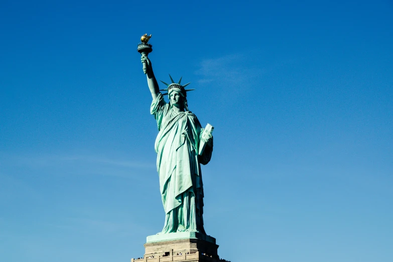 a statue of liberty against a blue sky, a statue, by Daniel Lieske, pexels contest winner, slide show, small stature, a quaint, exterior shot