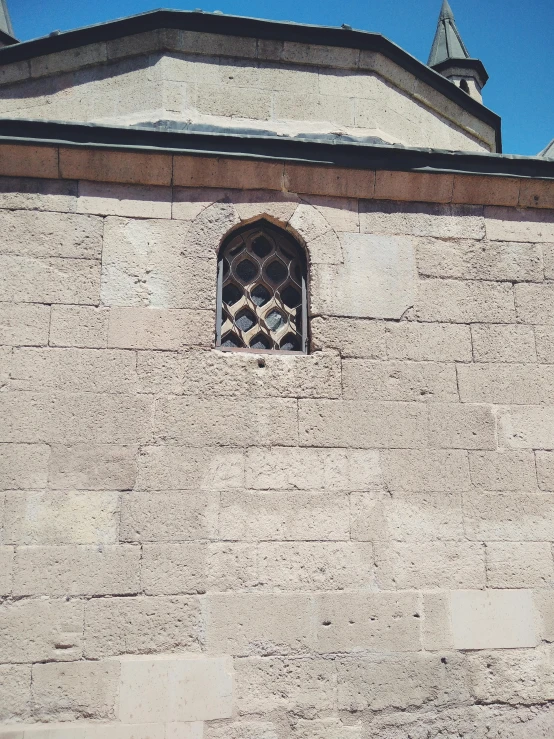 a clock mounted to the side of a stone building, an album cover, inspired by Modest Urgell, romanesque, windows and walls :5, low quality photo, mosque, pareidolia