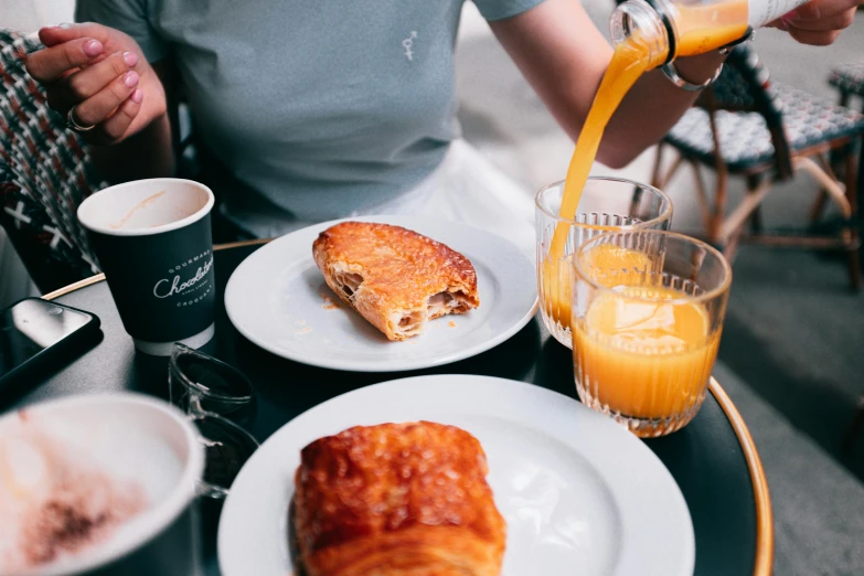 a person sitting at a table with plates of food and drinks, inspired by Richmond Barthé, pexels contest winner, breakfast, pastelle, pouring, manuka