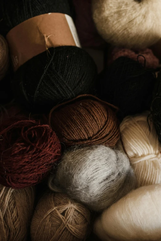 a pile of yarn sitting on top of a table, unsplash, arts and crafts movement, black and brown, ignant, half image, spheres