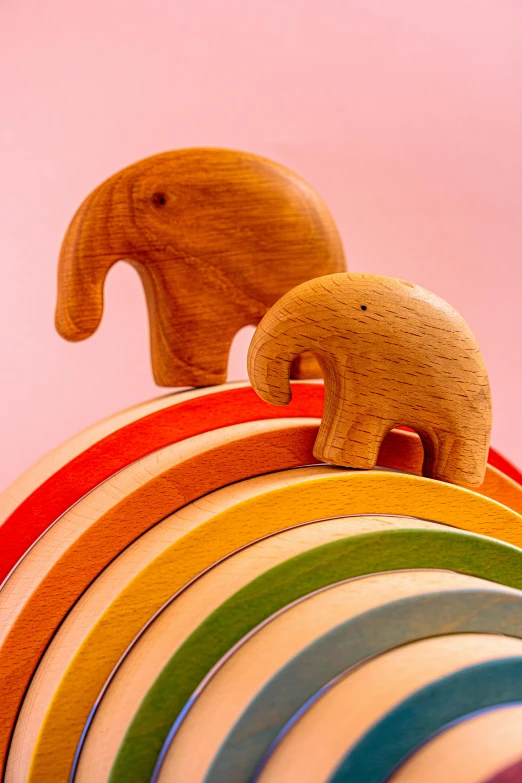 a couple of wooden elephants standing on top of a rainbow, circles, product shot, multiple stories, sustainable