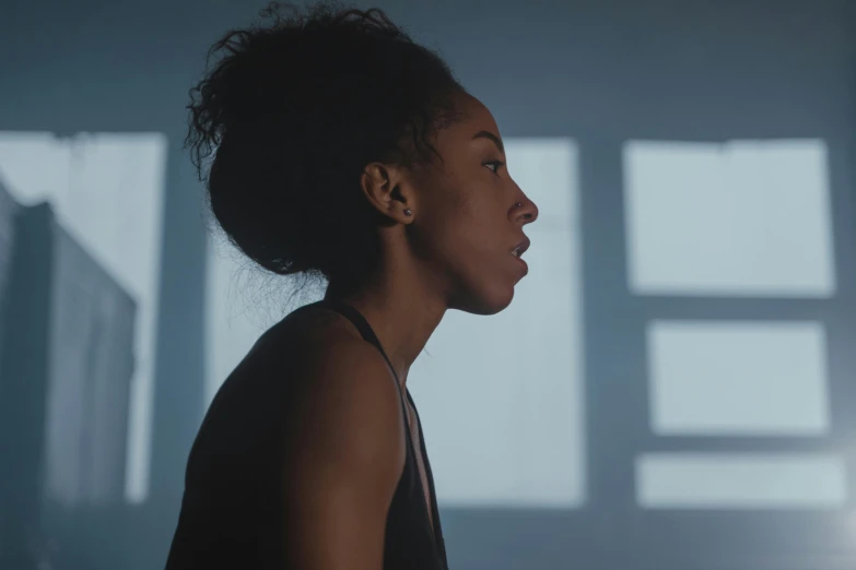 a woman standing in front of a window in a dark room, pexels contest winner, video art, ashteroth, close - up profile face, workout, ( ( theatrical ) )