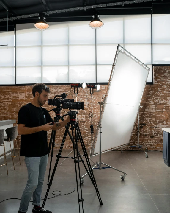 a man that is standing in front of a camera, trending on unsplash, video art, cinematic industrial lighting, bright daylight indoor photo, cctv footage of a movie set, low grain film