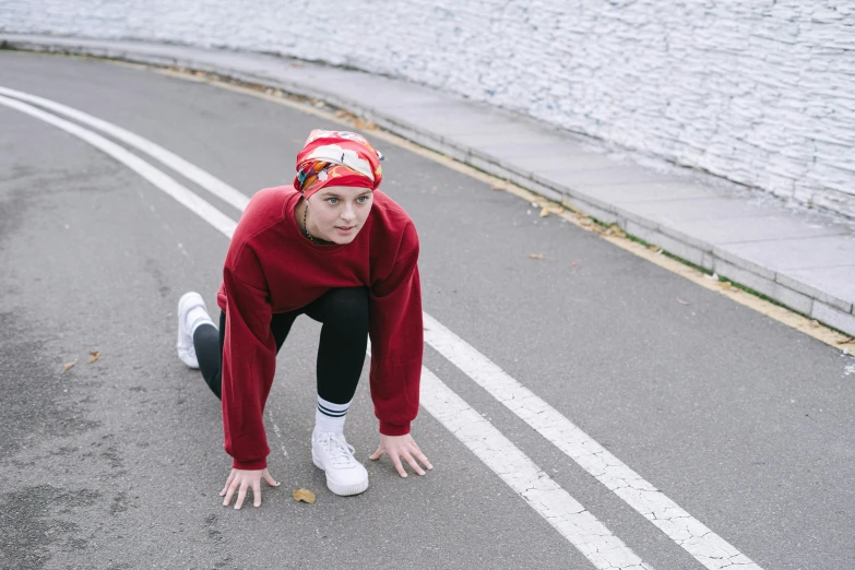 a woman squatting on the side of a road, pexels contest winner, red sweatband, non-binary, running, beanie