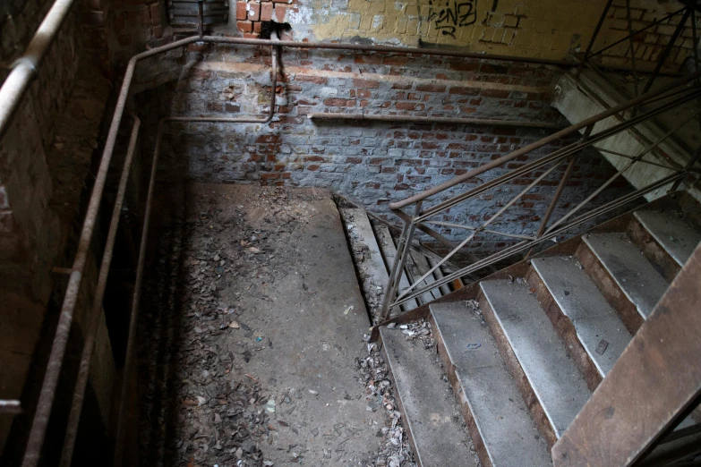 a stairwell in an abandoned building with graffiti on the walls, an album cover, pexels, brick debris, background image, high view, ((rust))