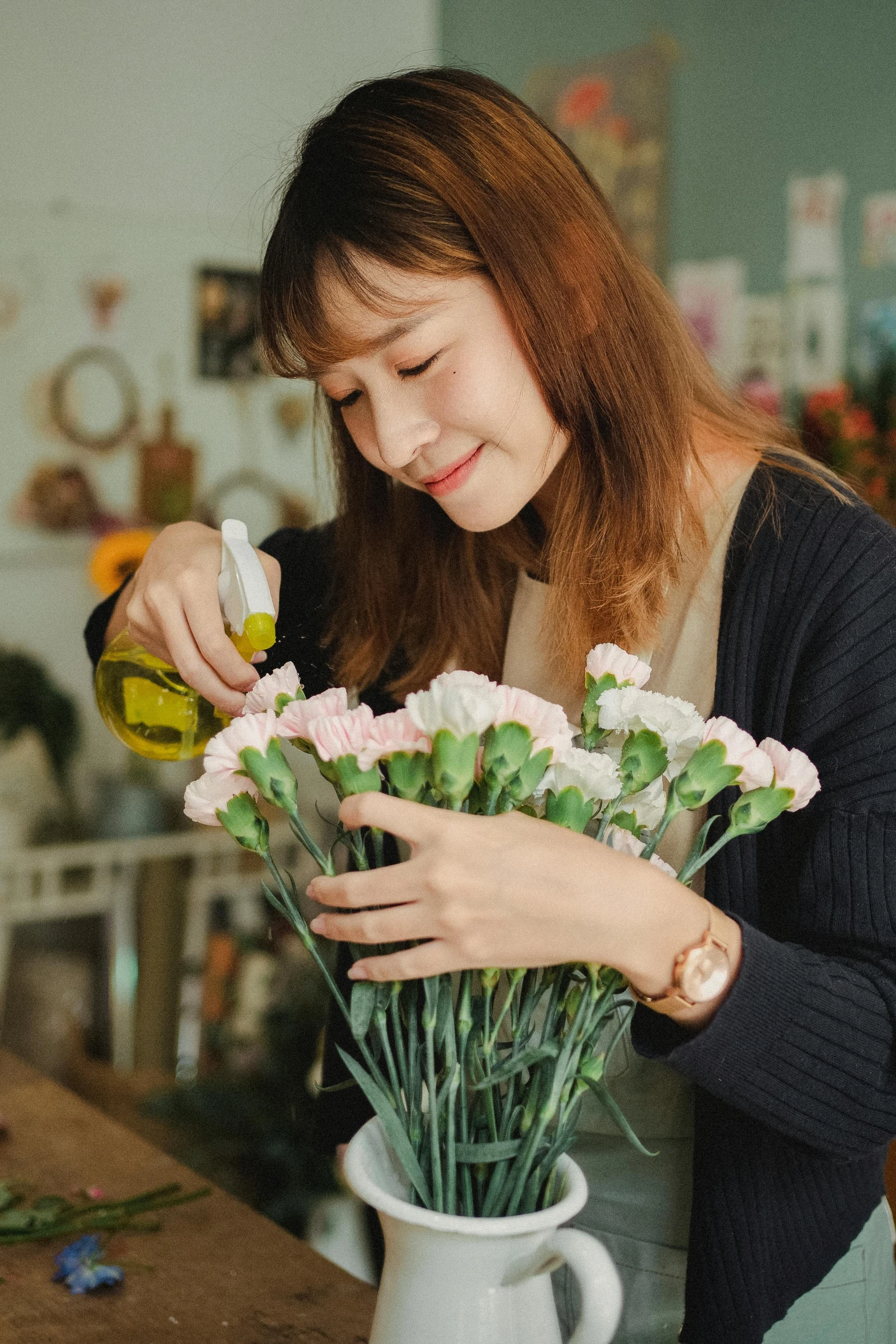 a woman is arranging flowers in a vase, pexels contest winner, beautiful young korean woman, cooking oil, 🌸 🌼 💮, fine detailing