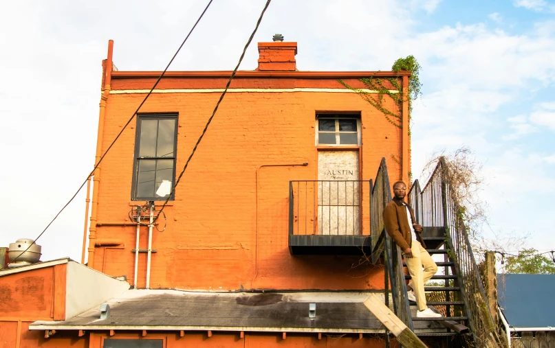 a fire hydrant sitting on the side of a building, an album cover, by Lee Loughridge, renaissance, orange roof, balcony, man standing, taken at golden hour