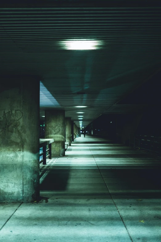 a couple of benches sitting next to each other, an album cover, inspired by Elsa Bleda, unsplash, conceptual art, dark corridors, overpass, dark teal lighting, concrete pillars