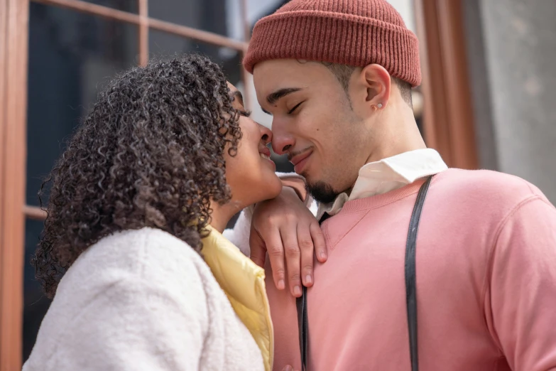 a man kissing a woman in front of a window, trending on pexels, photorealism, wearing a pink hoodie, mix of ethnicities and genders, romantic period, tongue