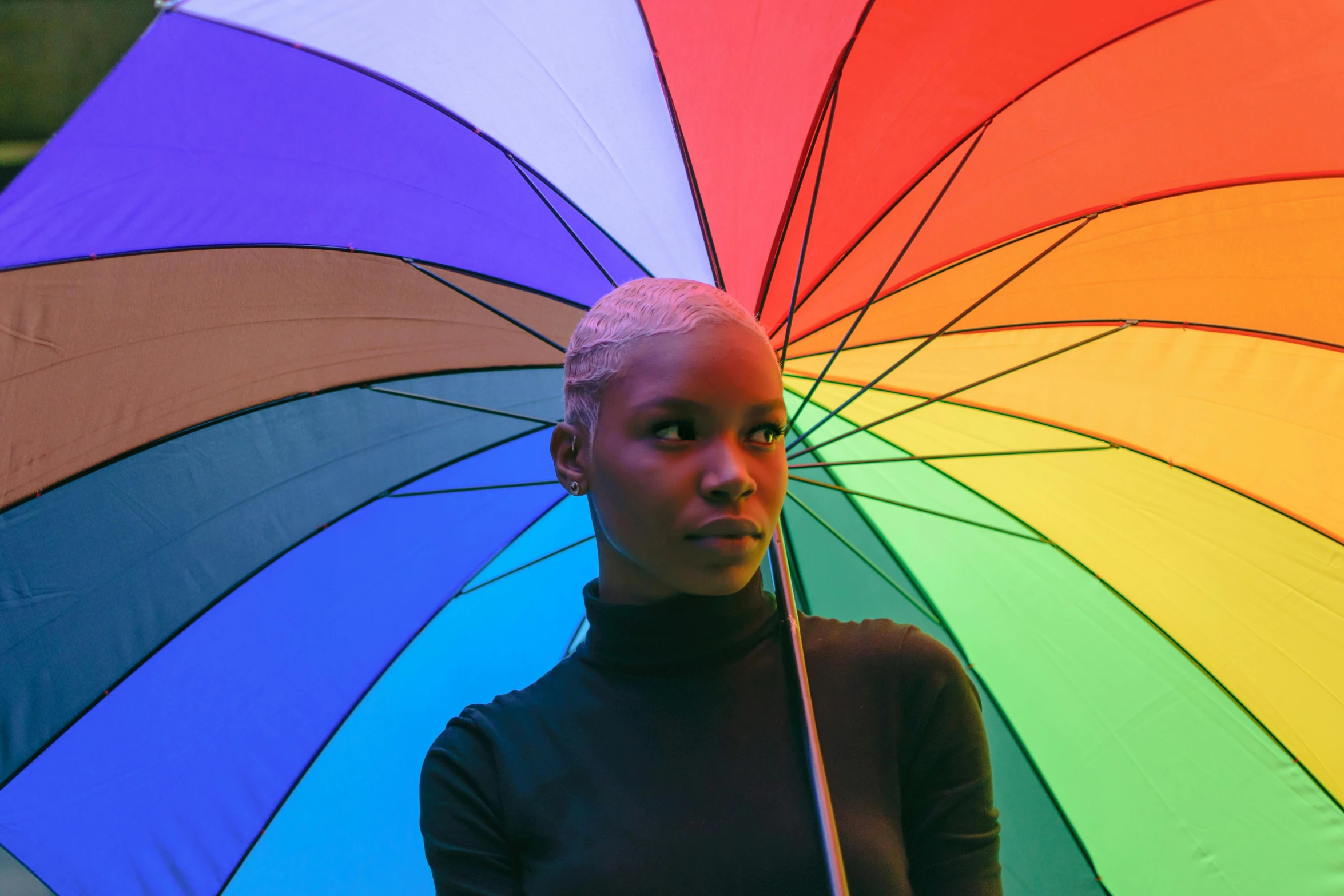 a woman standing under a rainbow colored umbrella, pexels contest winner, afrofuturism, portrait willow smith, adut akech, non-binary, black main color