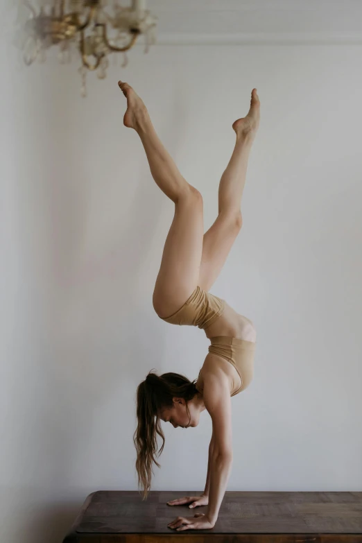 a woman doing a handstand on a wooden table, unsplash, arabesque, low quality photo, studio photo, sydney hanson, wearing leotard