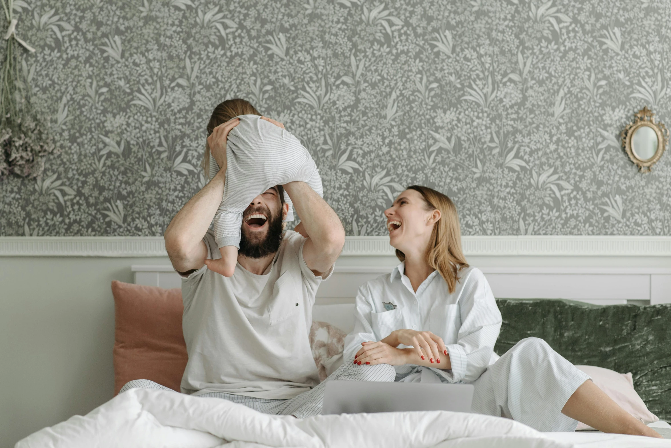 a man and a woman sitting on top of a bed, pexels contest winner, happening, happy family, laughing hysterically, grey, over it's head