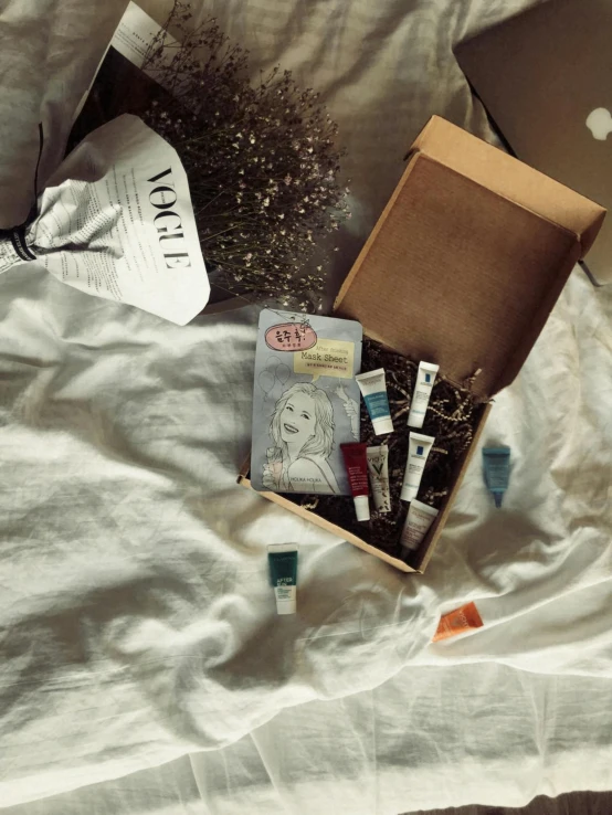 a box sitting on top of a bed next to a laptop, inspired by Eden Box, unsplash contest winner, serial art, small vials and pouches on belt, robe. perfect faces, vogue issue january, thumbnail