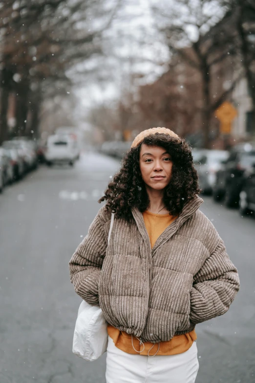 a woman walking down a street in the snow, trending on pexels, renaissance, mixed race, brown jacket, centered portrait, humans of new york